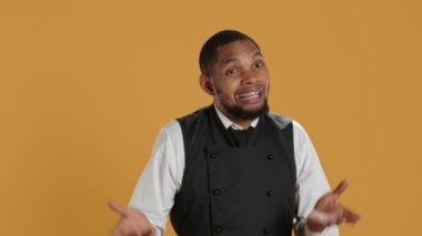 Profesyonel garson hiçbir şey bilmiyor ve emin değil, omuz silkiyor ve stüdyoda bilmediğimi söylüyor. Önlüklü şaşkın uşak bir şey hakkında kararsız ve kuşkulu hissediyor. Kamera A.