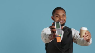 Otel hademesi ön masadaki elektronik işlemleri sembolize etmek için posizyon terminalini kartla gösteriyor. Üniformalı bellboy tatil köyündeki konaklama ve konfor için ödeme alıyor. Kamera A.