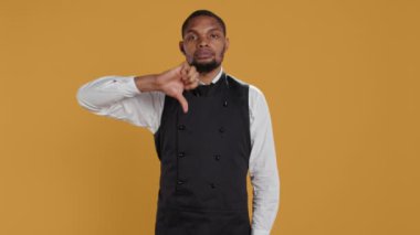 Ciddi şekilde hoşnutsuz garson stüdyoda anlaşmazlığını hoşnutsuz bir sembolle sunan bir işaret veriyor. Hayal kırıklığına uğramış yemek şirketi çalışanı memnuniyetsiz, olumsuz jest yapıyor. Kamera B.