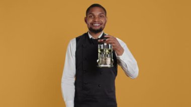 Mutlu garson el sallıyor ve müşterileri karşılıyor. Elinde müşterilere servis edilecek soslu bir şişe var. Lokantada insanları karşılayan neşeli, sevimli personel. Kamera B.