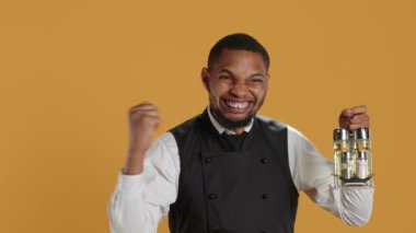 Mutlu garson sarı arka plana karşı tezahürat yapıyor, kendinden emin ve memnun. Çalışan, profesyonel hizmet görevinden duyduğu memnuniyeti dile getiriyor. Kamera A.