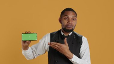 Profesyonelliğe sahip bir garson izole edilmiş bir model görüntüsü olan bir telefon tutuyor, yemek ve yemek endüstrisinde çalışıyor. Dost canlısı restoran çalışanları iş yerinde müşteri odaklı aktiviteler yapar. Kamera A.