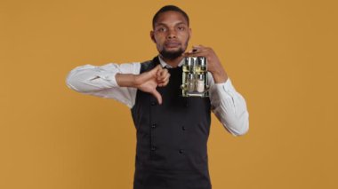 Restoran personeli sarı arka plana başparmak işareti koyuyor, masalarda gerekli soslarla dolu bir şişe taşıyor. Müşteri hizmetleri sektöründe garson, hoşnutsuzluk sembolü. Kamera B.