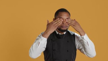 Restoran çalışanları onun gözlerini, ağzını ve kulaklarını kapatarak stüdyodaki kötülüğe karşı üç bilge maymun metaforu sunuyorlar. Garson konukseverlik endüstrisini ne görüyor, ne duyuyor, ne de konuşuyor. Kamera A.