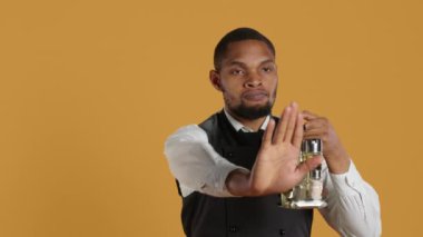 Üniformalı garson, stüdyo 'da elinde avucuyla dur işareti, olumsuz bir sembol ve bir şeyi reddediyor. Reddedildiğini ve tatmin olmadığını gösteriyor. Kamera A.