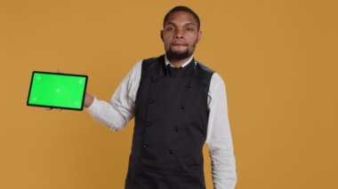 Yemek şirketi çalışanı önlük giyip müşterilerine servis yaparken izole bir kroma anahtar görüntüsü sunuyor. Profesyonel giyimli konukseverlik sektörü personeli, müşteri memnuniyeti. Kamera B.