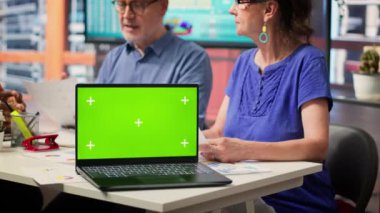 Yaşlı müşteriler danışmanıyla emeklilik planının güvenliğini tartışıyor, modern ofiste dizüstü bilgisayarlarında kroma anahtarı var. Yaşlılar hayat sigortası için emeklilik seçeneği sunuyor. Kamera A.