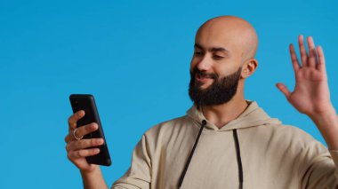 Modern adam video çağrılarına cevap veriyor ve el sallıyor, arkadaşlarıyla konuşmak için internetteki video konferans bağlantısında buluşuyor. Genç bir Arap uzaktan sohbetle insanlarla konuşuyor. Kamera 2.