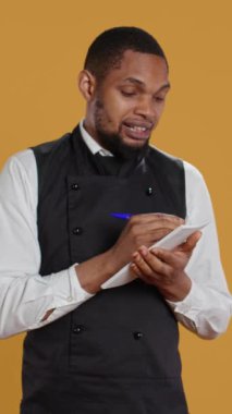 Önlüklü Dikey Video Becerikli Garson müşterilerden yemek siparişlerini bir deftere alır ve müşteri memnuniyeti için önemli bilgiler yazar. Hizmet sektöründe çalışan kahya.