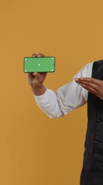 Profesyonelliğe sahip dikey video garson izole edilmiş bir model ekranı olan bir telefon tutuyor, yemek ve yemek endüstrisinde çalışıyor. Dost canlısı restoran çalışanları iş yerinde müşteri odaklı faaliyet gösteriyor.
