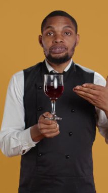 Dikey Video Restoran çalışanı müşterilerine masada bir bardak kırmızı şarap getirip beş yıldızlı bir lokantada servis ediyor. Profesyonel garson müşteri memnuniyetine odaklanıyor. Kamera B.