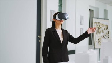 Ofiste VR kulaklığı takılı yeni bir proje üzerinde çalışan mimar, unicorn iş ajansının mülkünü yenilemek için endüstriyel plan geliştiriyor. Sanal gerçeklik teknolojisi kullanan bir kadın.