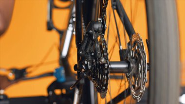 Performans değerlendirmesi sırasında kadınlar tarafından incelenen bisiklet tekerleği mekanizmasını yakından çek. Bulanık arka planda profesyonel tarafından test edilen bisiklet bileşenlerine odaklanın.