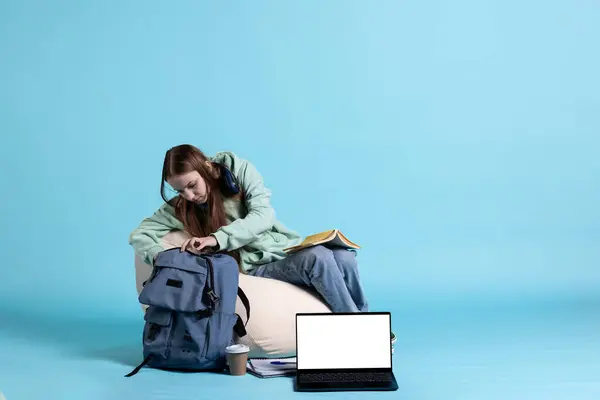 stock image Woman browsing through backpack, isolated over studio background. Teenager taking out school textbooks out of rucksack used during commuting to university, studio backdrop