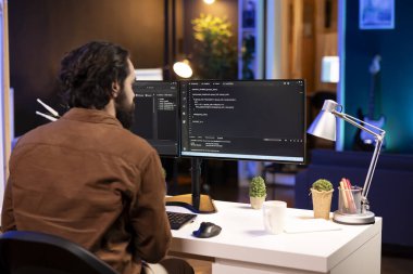 Bilgisayar operatörü evdeki PC 'de yazılım hata ayıklaması yapıyor, monitörlerdeki bozuk kod satırlarını kontrol ediyor. Daire kodlama sorunları çözme ve klavyede yazma konusunda bilişim uzmanı