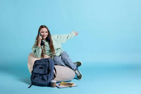 stock image Happy girl receiving telephone call, saluting friends, using cellphone. Teenager having fun catching up with school colleagues during phone call, isolated over studio backdrop