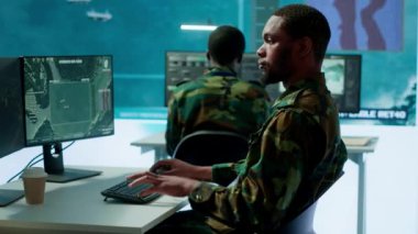 Yüksek teknolojili bir komuta merkezindeki askeri personel uydu görüntülerini izler, istihbarat operasyonlarını koordine eder. Ulusal güvenliği sağlamak ve stratejik ordu misyonlarını desteklemek. Kamera A.