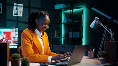 Kendini işine adamış bir kadın ev ofisinin rahatlığı içinde özenle dizüstü bilgisayarda yazı yazıyor, üniversite ödevini bitirmek için okul ödevi yazıyor. Afrikalı Amerikalı öğrenci bilgiyi geliştirmek için çalışıyor. Kamera B.