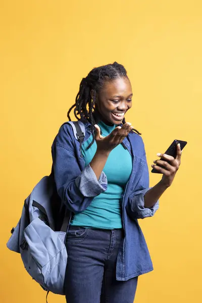 stock image Woman using smartphone laughing at hilarious social media posts on feed. Jolly african american girl browsing internet websites, amused by funny memes, isolated over studio background