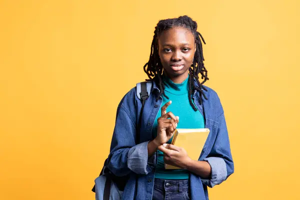 stock image Portrait of african american woman carrying textbook, gathering information for school exam, isolated over studio background. Girl holding encyclopedic book, preparing for university assessment