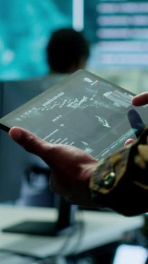 Dikey Video Askeri Subayı, yüksek teknolojili bir operasyon odasında veri koruması sağlayan siber güvenlik operasyonlarını yönetiyor. Güvenlik kameraları, uydu görüntüleriyle çalışan askerler.