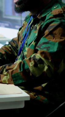 Dikey video askeri kontrol odasında ordu personeli izleme sistemleri, verileri birleştiren ve stratejik görevleri koordine eden askerler bulunuyor. Karar verme ve verimliliği destekle