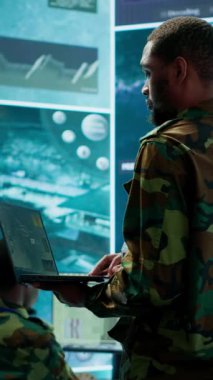 Askeri uzmanlardan oluşan dikey video ekibi gizli servis komuta merkezinde çalışır, gizli bilgilerin güvenliği ve güvenliğini sağlamak için izleme sistemleri ve veri korumasını yönetir.