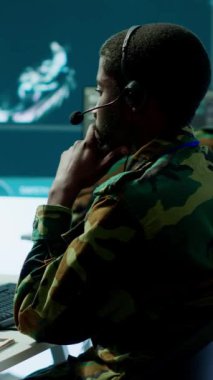 Üniformalı dikey video ordu profesyoneli bir görev kontrol merkezinde çalışıyor, gözetleme sistemlerini koordine ediyor ve operasyonlar için istihbarat verilerini işliyor. Stratejik planlamanın sağlanması ve