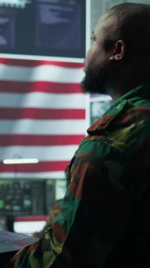 Amerikan askeri üniformalı dikey video istihbarat memurları bir komuta noktasındaki bilgisayarlar üzerinde çalışırlar, gözlem ve veri analizlerini yönetirler. ABD hükümeti için küresel operasyonları destekleyin. Kamera.