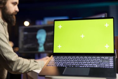 Zihni bilgisayara yüklemek için bulanık arka planda EEG kulaklık takan mühendisin kullandığı yeşil ekran laptopuna odaklan. Bilgi işlem uzmanlarının beyin yüklemek için kullandığı model dizüstü bilgisayarın kapatılması