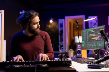 Ev stüdyosunda elektronik piyano klavyesi çalan müzik yapımcısı yeni şarkılar yaratmak için Midi Control notaları kaydediyor. Sentezleyici tuşlar üreten genç sanatçı, post prodüksiyon teknikleri.