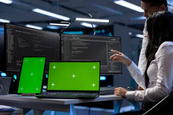 stock image Engineers in data center using mockup tablet and laptop to check for server issues arising due to high CPU usage. Server hub workers fixing insufficient memory errors with green screen devices