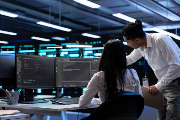 Teamworking technicians in server room looking to find network issues affecting supercomputer performance. IT experts fixing slow data transfer rates in data center equipment