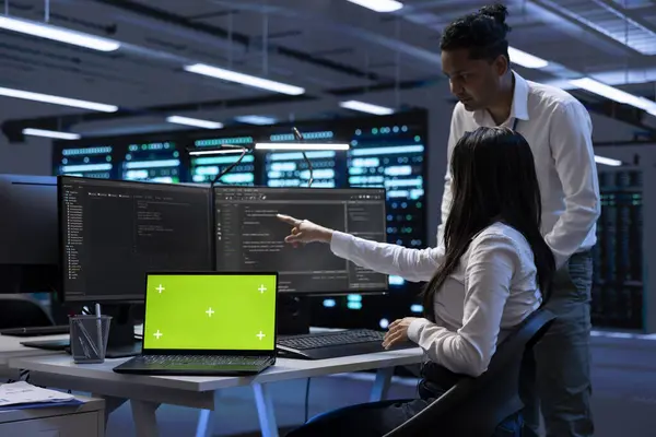 stock image Team of technicians using mockup laptop to check server clusters configuration settings. Teamworking experts checking event logs in monitoring software to find faulty data center hardware root cause