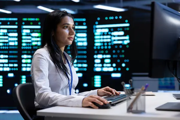 stock image Indian woman doing yearly checkup to prolong data center electronics life span and avoid downtime. IT employee in server room monitoring server infrastructure components using PC