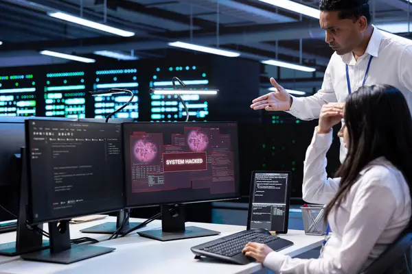 stock image Computer scientist in server hub asking coworker for help, trying to protect equipment from hacker. IT specialist in data center facility requesting assistance to fix security breach alert