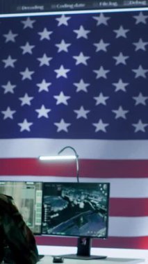 Yüksek teknoloji ofisindeki tehdit tespit faaliyetlerini denetleyen dikey video askeri subayı büyük ekrandaki çok gizli verileri inceliyor. Amerikan askerleri hibrit savaşı ve siber saldırıyı yönetiyor.