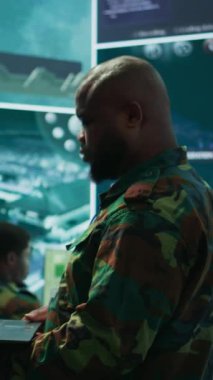Dikey video siber güvenlik ekibi gelişmiş bir askeri komuta merkezinde, gözetim sistemlerinde ve veri korumasında çalışıyor. Ordu personeli yüksek teknoloji kullanarak ulusal güvenlik operasyonlarında çalışıyor.