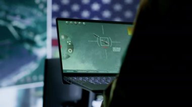 Amerikan askeri üniformalı istihbarat memurları bir komuta merkezinde bilgisayar üzerinde çalışıyor, gözlem ve veri analizini yönetiyorlar. ABD hükümeti için küresel operasyonları destekleyin. Kamera A.