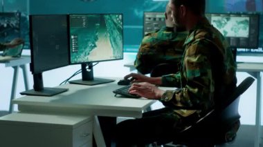 Görev kontrol merkezindeki askeri uzmanlar uydu görüntülerini analiz etmek için bilgisayar ve büyük ekran üzerinde modern teknoloji kullanıyorlar. İstihbarat operasyonları için potansiyel tehditleri takip eden bir uzman. Kamera A.