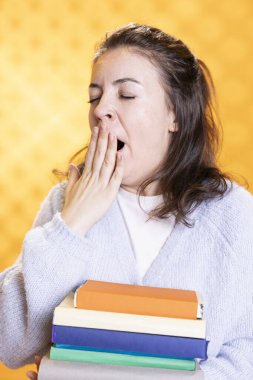 Esneyen, stresten bitap düşmüş hisseden bir kadın, okul sınavı için kitap taşıyan, stüdyo geçmişi olan. Üniversite değerlendirmesinden önce bütün gece ödev yaptıktan sonra yorgun öğrenci uykulu hissediyor.