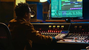 Afrika kökenli Amerikalı ses uzmanı hareket eden faders ve renkli metrelerle ses konsolunda çalışır, profesyonel stüdyo kontrol odasında düzenleme yapar. Yapımcı albüm üzerinde çalışıyor, hit şarkılar kaydediyor. Kamera A.