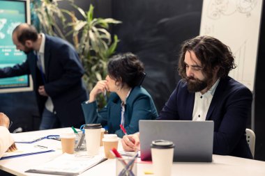 Düzenleyici değişiklikler veya endüstri standartları hakkındaki güncellemeleri gözden geçirmek üzere bir bilgi paylaşım konferansında pazarlama ekibi toplantısı. İş arkadaşları tüm veri analiz raporlarını inceliyor.