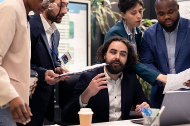 Yönetici, personelinin hafta sonunda ne üzerinde çalıştığını değerlendiriyor ve küresel kalkınma projesinin ayrıntılarını inceliyor. Denetmen ekip lideri veri raporlarını ve sonuçları okuyor..