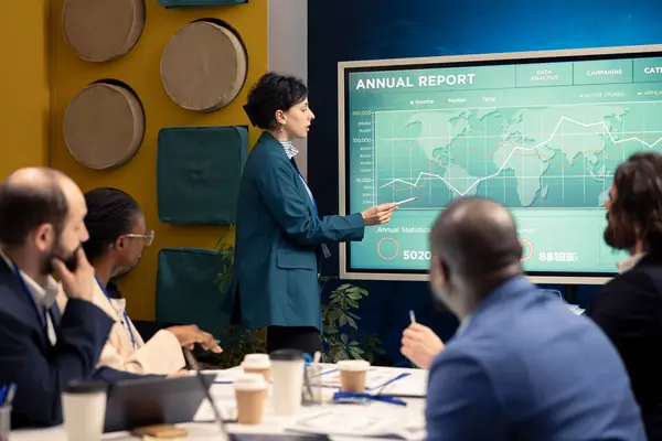 stock image Marketing specialist showing infographics in a status update meeting, studying customer satisfaction and retention with annual data reports. Employee operating interactive board.