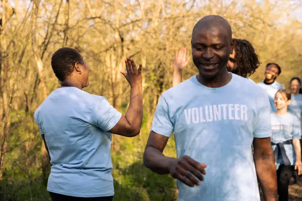 stock image Team of volunteers sharing high five praising each other after a successful activity, finishing garbage and plastic cleanup. Proud joyful environmentalists enjoying their preservation mission.