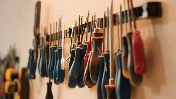 stock image Chisels, screwdrivers, wrench and pliers on wall in furniture assembly shop, panning shot. Close up of various woodworking tools on rack in joinery used for working with wood materials