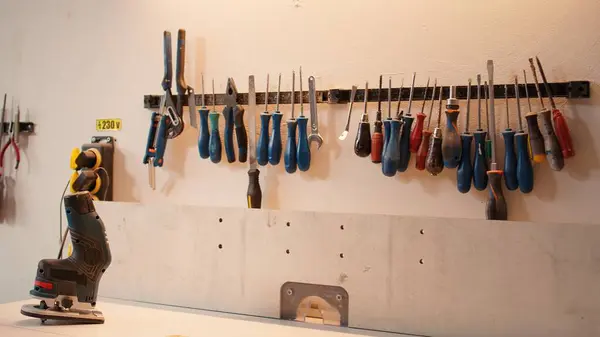 stock image Chisels, screwdrivers, wrench and pliers on wall in carpentry studio, panning shot. Close up of various woodworking tools on rack in workshop used for repairing or creating wooden objects