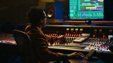 Kontrol odasındaki sesleri ses konsolu ve profesyonel kurgu yazılımı ile birlikte bilgisayarda takip ve karıştırma mühendisleri. Müzik prodüksiyon uzmanı motorlu faders ve knobs kullanıyor. Kamera A.