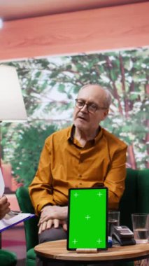 Dikey Video Tıp Asistanı, yaşlılara reçeteli bir tedavi uyguluyor ve evlerinde taklit yeri olan tablet kullanıyor. Hemşireler ilaç ve profesyonel tavsiyelerde bulunuyorlar.